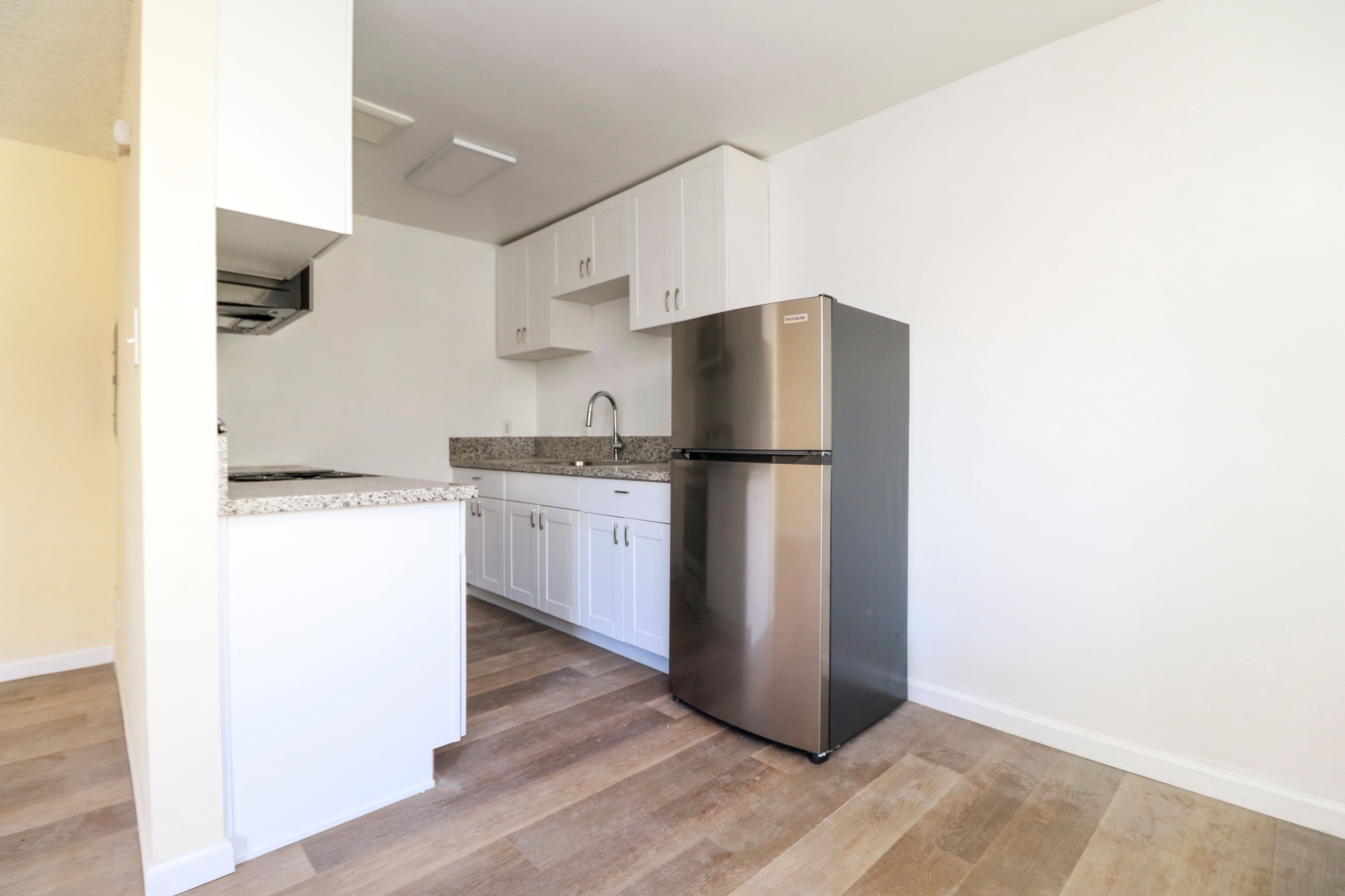 A kitchen with a stainless steel refrigerator and white cabinets.
